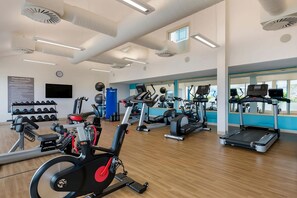 A gym with various exercise equipment, including treadmills and stationary bikes, and a wall-mounted TV. - Amazing Sea Views Condo 3rd Floor with all amenities (Simpson Bay)