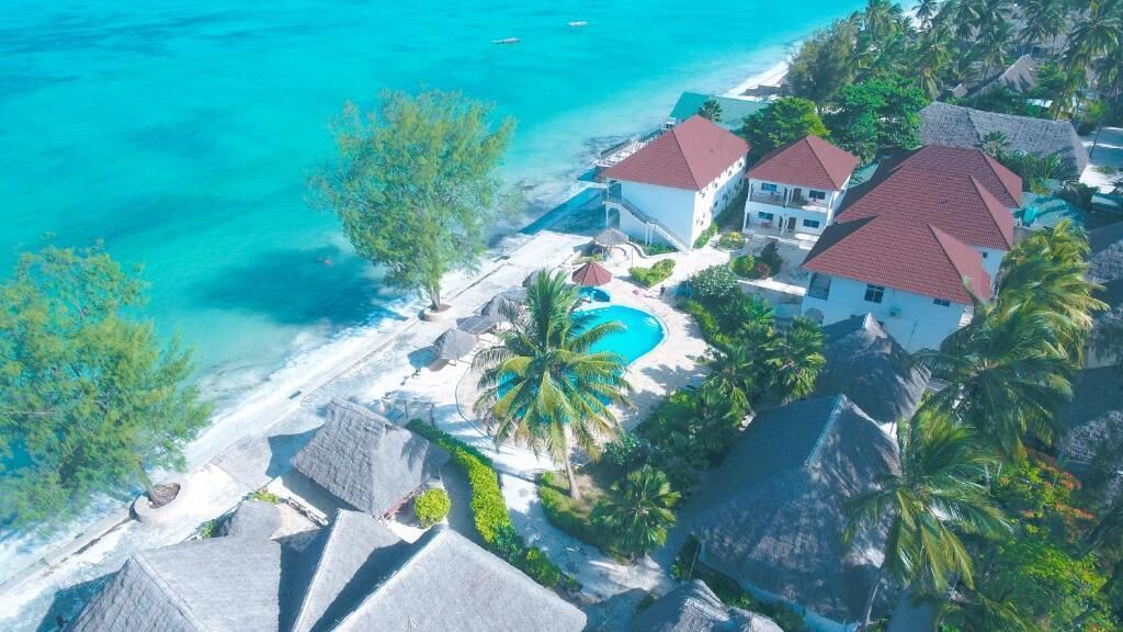 A coastal property with a swimming pool, multiple buildings, and a beach.