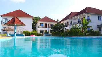 Un hotel con piscina, varias edificaciones con techos rojos y abundante vegetación.