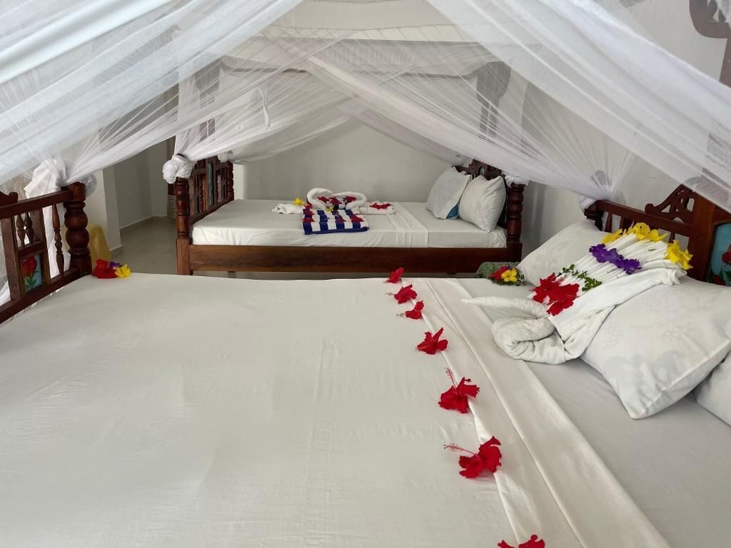 Un dormitorio con cama con dosel, un sofá cama independiente y una mesita de noche con lámpara.
