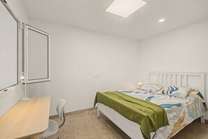 A bedroom with a bed, a desk, a chair, a standing lamp, and a ceiling light. - Vacation Apartment 'The Cliff View B' with Sea View, Private Terrace and Wi-Fi (La Estrella)