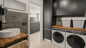 Moderni keittiö, jossa on sisäänrakennettu pesukone, allas ja tummat keittiökaapit.