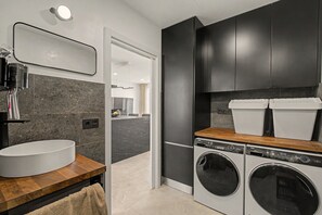 A modern kitchen with a built-in washing machine, a sink, and dark cabinetry. - Vacation Apartment 'The Cliff View B' with Sea View, Private Terrace and Wi-Fi (La Estrella)