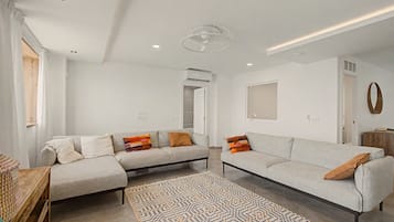A modern living room with a sofa set, a patterned rug, and a ceiling fan.