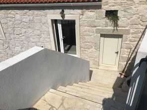 A stone building with a door, a small window, and a step leading to a lower level.