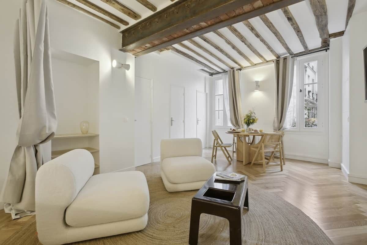 Ein modernes Wohnzimmer mit Holzboden, einer Couch, einem Couchtisch und einem Essbereich mit Stühlen und Tisch.
