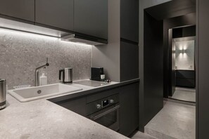 A modern kitchen with a double sink, stainless steel faucet, and a built-in oven. - Grand confort au pied du Louvre (Paris)