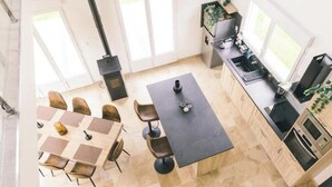 Een moderne keuken met een centraal eiland, een eethoek met stoelen en grote ramen.