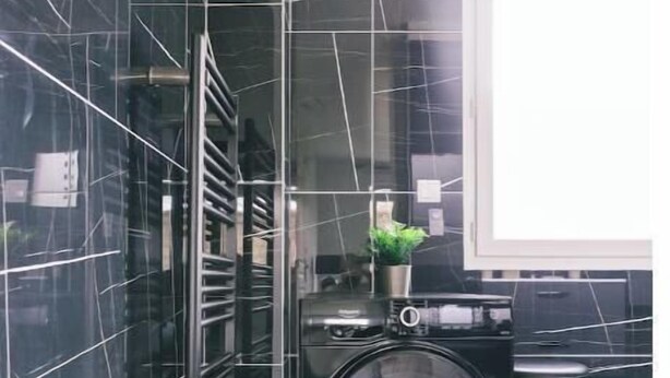 Een moderne keuken met een ingebouwde wasmachine en droger, een roestvrijstalen spoelbak en een raam dat voor natuurlijk licht zorgt.