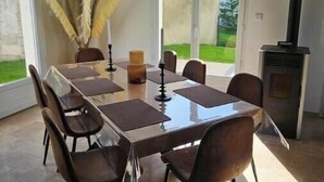 Een eetgedeelte met een lange tafel, stoelen en een open haard.