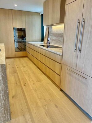 A modern kitchen with wooden cabinets, a countertop, and a built-in oven. - Luxury 2BR Apt, Pool, Parking, Skye Kangaroo Pt (Kangaroo Point)