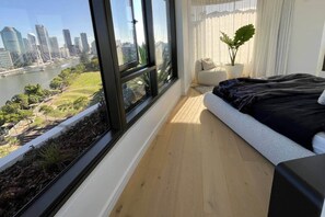 A bedroom with a large window overlooking a cityscape and a river. - Luxury 2BR Apt, Pool, Parking, Skye Kangaroo Pt (Kangaroo Point)