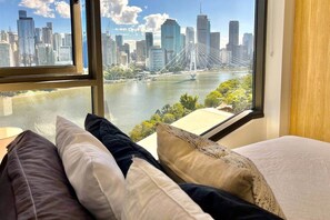 A room with a bed and a large window overlooking a city skyline and a river. - Luxury 2BR Apt, Pool, Parking, Skye Kangaroo Pt (Kangaroo Point)