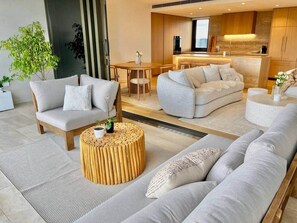 A modern living room with sofas, a coffee table, and a kitchen area in the background. - Luxury 2BR Apt, Pool, Parking, Skye Kangaroo Pt (Kangaroo Point)