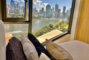 A hotel room with a large window offering a view of a city skyline and a river. - Luxury 2BR Apt, Pool, Parking, Skye Kangaroo Pt (Kangaroo Point)