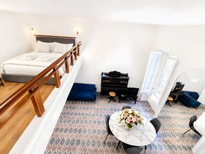 A bedroom with a bed, a desk, a chair, a small table with a vase of flowers, and a patterned floor. - Apartment 'Navona Haven' with Wi-Fi and Air Conditioning (Rome)