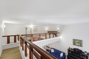 A multi-level living space with a wooden staircase, a blue sofa, a black piano, and a framed picture on the wall. - Apartment 'Navona Haven' with Wi-Fi and Air Conditioning (Rome)