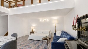 A hotel room with a bed, a blue sofa, a small table, a lamp, and a decorative candelabra. - Apartment 'Navona Haven' with Wi-Fi and Air Conditioning (Rome)