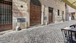 A cobblestone street with a historic building featuring a large wooden door, stone walls, and a metal gate. - Apartment 'Navona Haven' with Wi-Fi and Air Conditioning (Rome)
