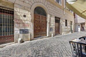 A cobblestone street with a historic building featuring a large wooden door, stone walls, and a metal gate. - Apartment 'Navona Haven' with Wi-Fi and Air Conditioning (Rome)
