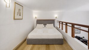 A hotel room with a bed, a headboard, a wooden railing, and a framed picture on the wall. - Apartment 'Navona Haven' with Wi-Fi and Air Conditioning (Rome)