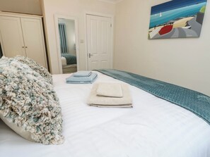 A bedroom with a bed, a painting, a wardrobe, and a door. - The Old Post Office (Ventnor)