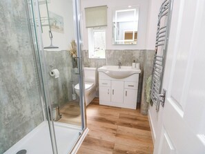 A bathroom with a glass shower enclosure, a toilet, a sink with a mirror, and a towel rack. - The Old Post Office (Ventnor)