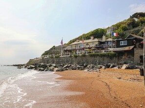 Un hotel a la costa amb una bandera, un rètol que diu 'SPYGLASS INN' i una costa rocosa.