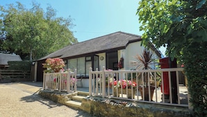 Une maison à deux étages avec un balcon, une allée en gravier et un mur en pierre.