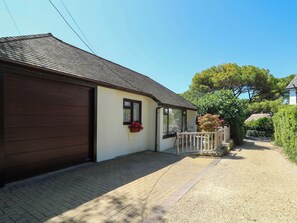 A residential property with a garage, a covered porch, and a pathway leading to the house. - The Old Post Office (Ventnor)