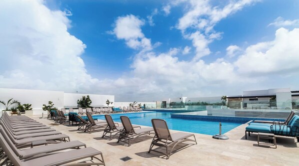 A rooftop pool area with lounge chairs and a clear view of the sky. - 1BR condo w/ pool & gym (Playa del Carmen)