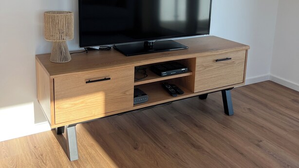 A wooden entertainment center with a flat-screen TV, drawers, and a lamp.