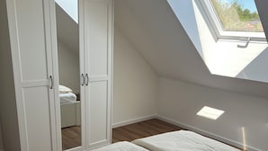 A bedroom with a skylight, a wardrobe, and a bed.