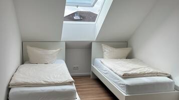 Ein kleines, modernes Schlafzimmer mit zwei Betten, einem Oberlicht und Holzboden.