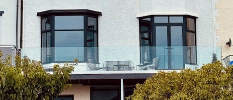 Una casa de dos pisos con techo plano, ventanas amplias y un balcón.