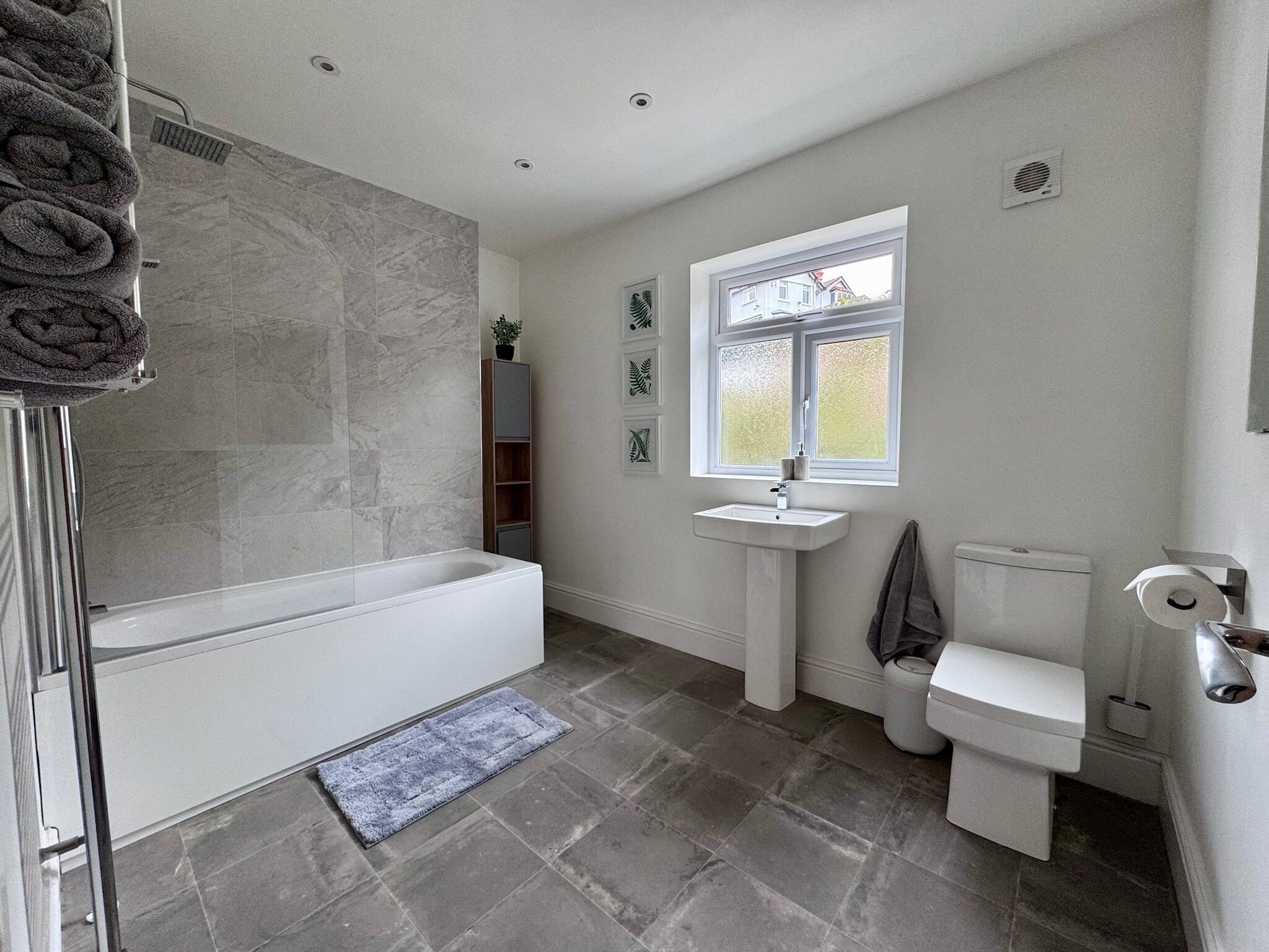 A bathroom with a bathtub, toilet, sink, and a window.