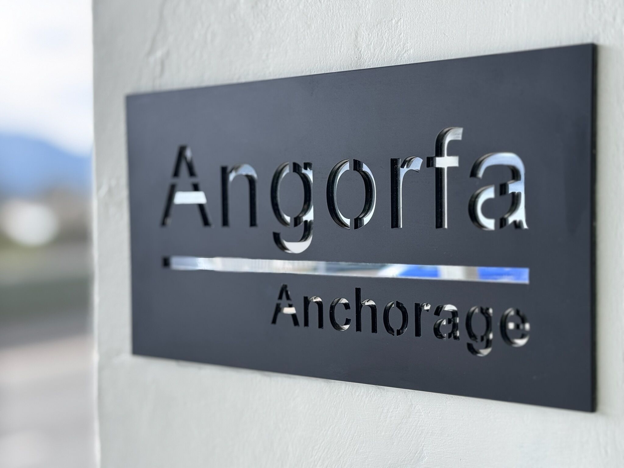 A metallic sign with the name 'Angorfa Anchorage' mounted on a wall.