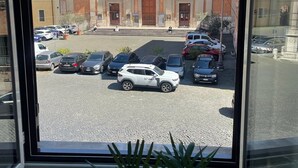 A building with a central dome and a cross on top, surrounded by parked cars and a cobblestone street. - Rooms with a View, Trastevere Home Rental (Roma)