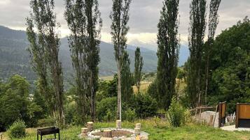 Un espacio al aire libre con césped y una disposición circular de troncos, un banco y una estructura de madera.