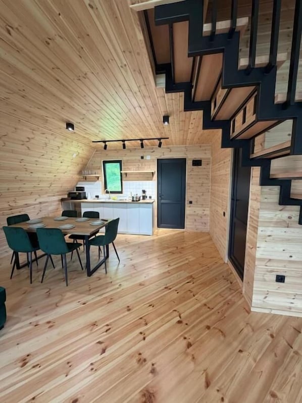 Un interior de madera con comedor, cocina y escalera.