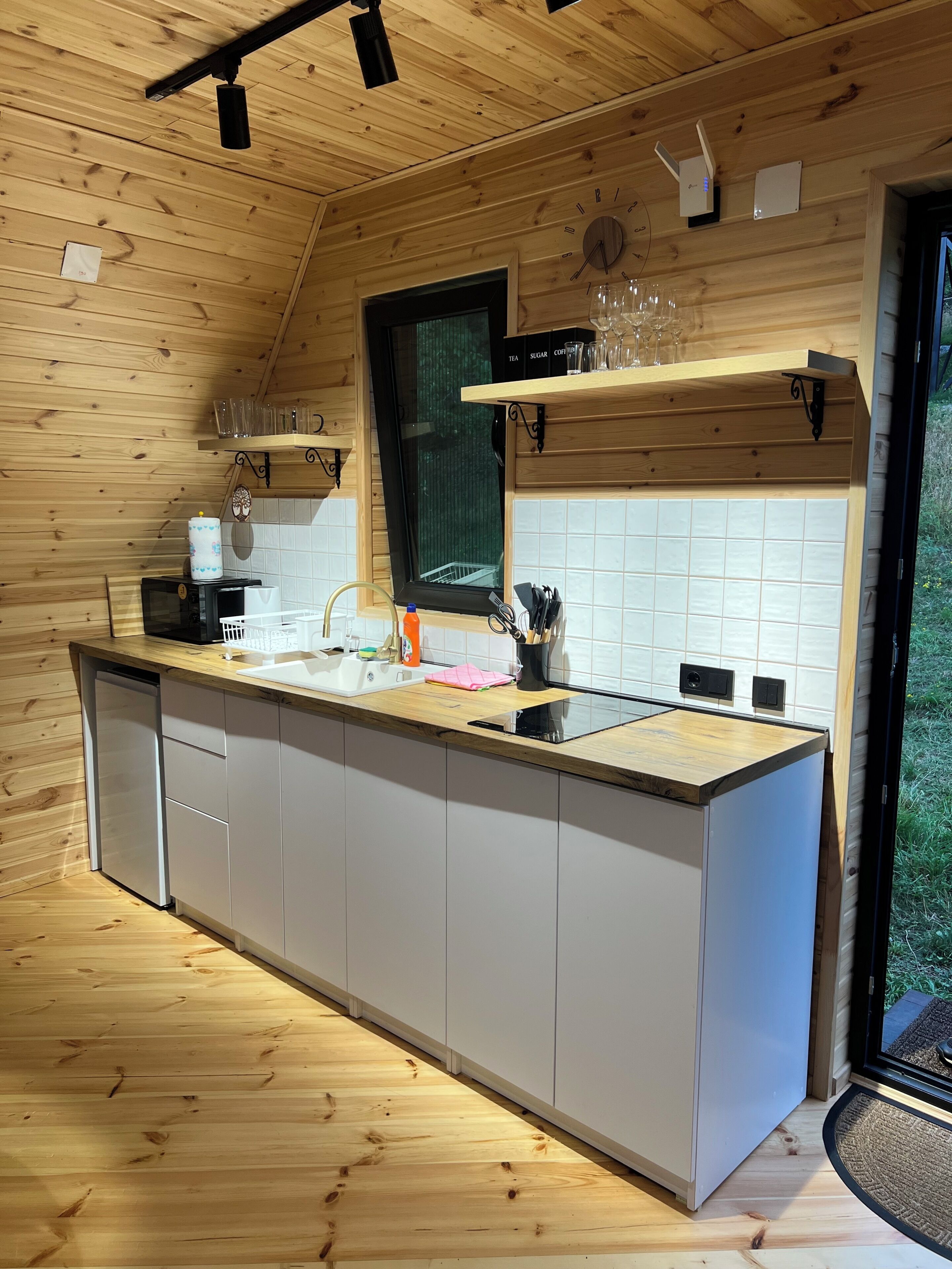 Une cuisine moderne avec des meubles en bois, un îlot central, un four encastré et une fenêtre donnant sur un espace verdoyant.