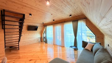 A wooden interior with a sofa, a TV, and a staircase.
