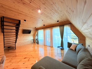A wooden interior with a sofa, a TV, and a staircase.