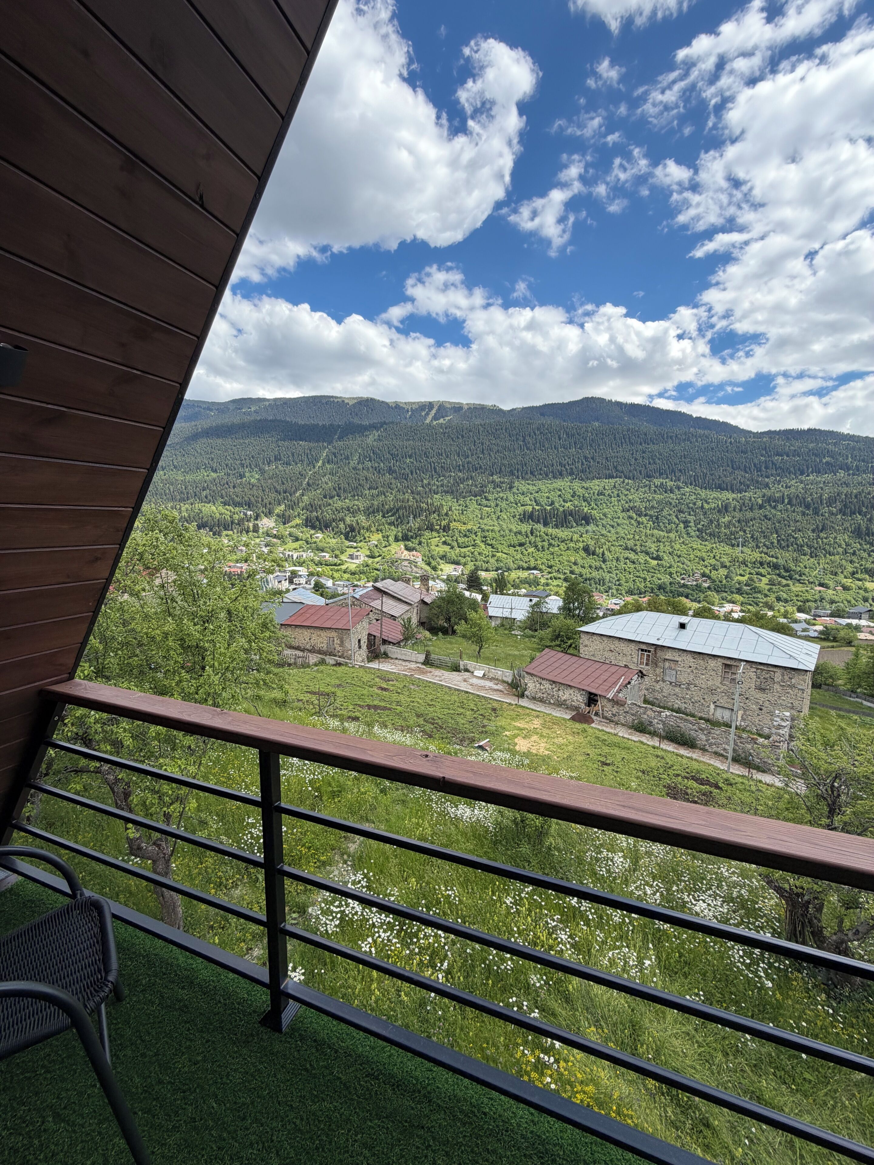 A balcony with a view of a village, mountains, and a clear sky.