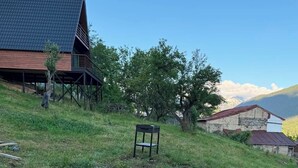 Un jardín con un cantero circular de grava, un banco de madera y un edificio con techo inclinado al fondo.