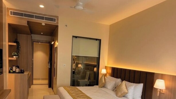 Quarto de hotel moderno com uma cama grande, mesas de cabeceira, escrivaninha e um espaço de estar.