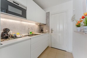 Eine moderne Küche mit weißen Schränken, einem eingebauten Backofen, einer Spüle und einer Arbeitsfläche mit verschiedenen Gegenständen.