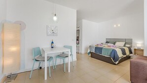 A modern bedroom with a bed, bedside table, and a small sitting area with a table and chairs. - Home Holidays 204 (CN)