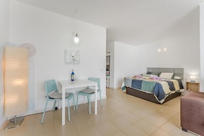 Ein modernes Schlafzimmer mit Bett, Nachttisch und einer kleinen Sitzecke mit Tisch und Stühlen.