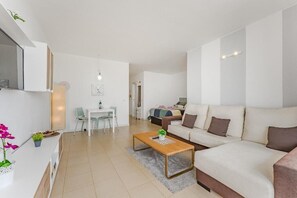 A modern living room with a sofa, coffee table, and a dining area with chairs. - Home Holidays 204 (CN)
